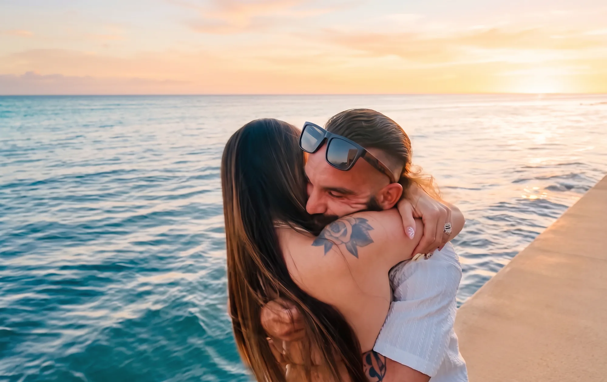 Megan and Gage holding each other as the sun sets over the Pacific