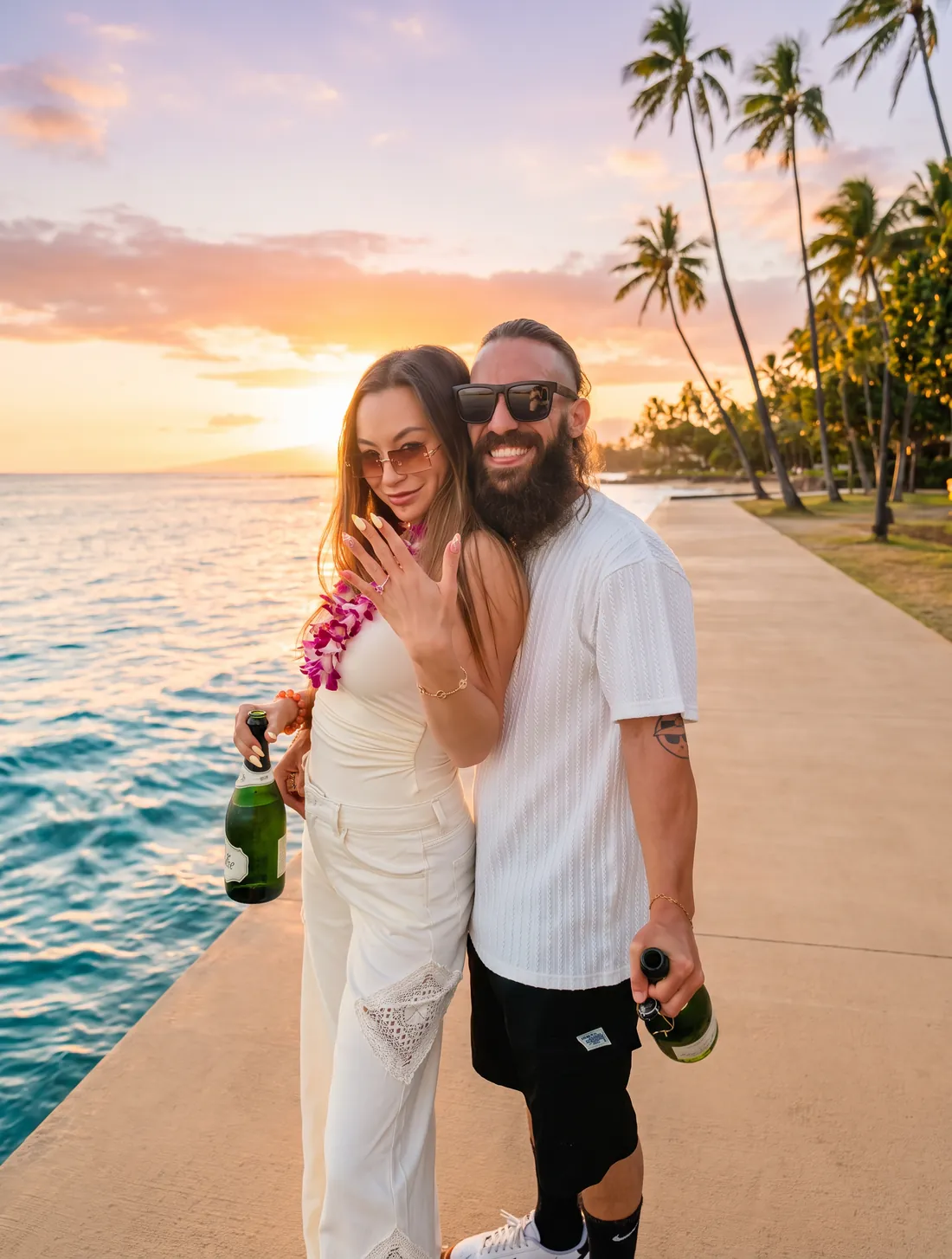 Megan showing the ring, champagne in hand at sunset