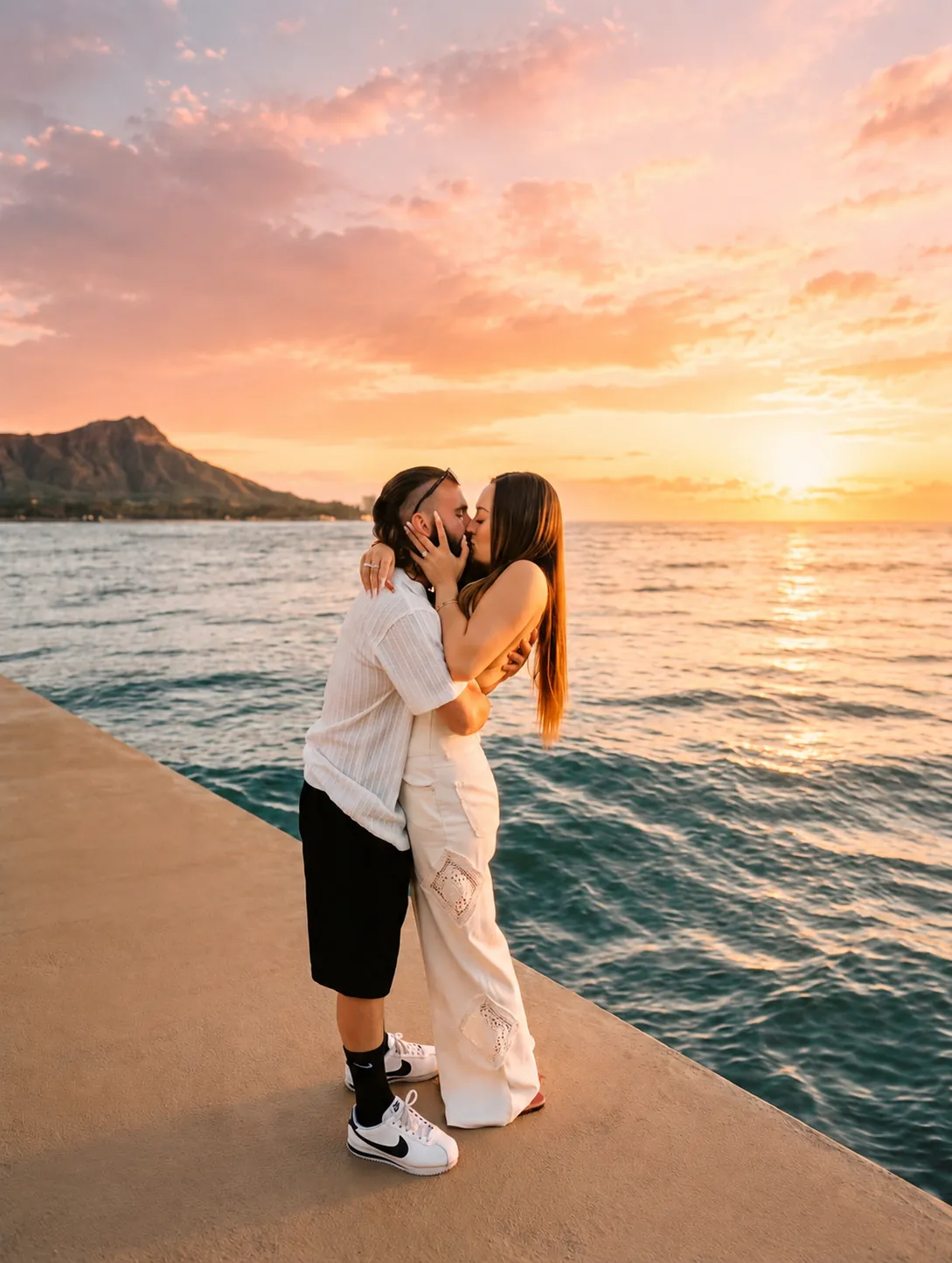 Megan and Gage kissing in front of Diamond Head at sunset